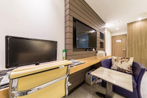 a room with a tv and a desk with a chair at Guwol Hotel in Incheon