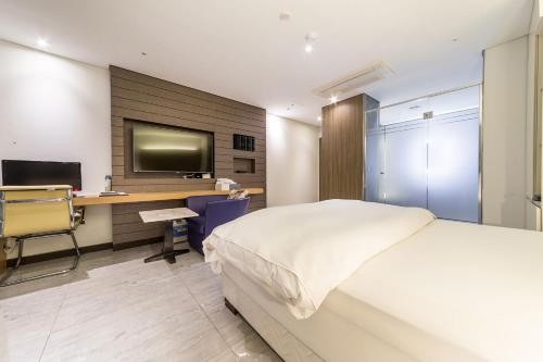 a bedroom with a bed and a desk with a computer at Guwol Hotel in Incheon