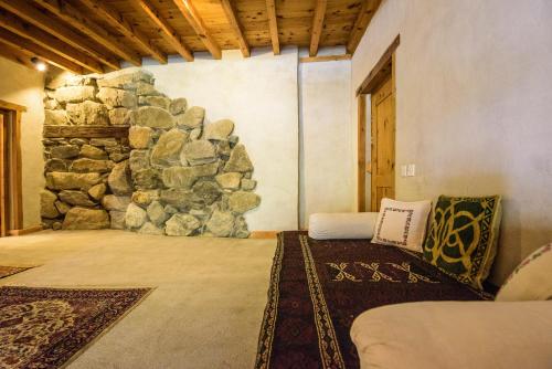 a room with a stone wall with a bed and a rock wall at Serena Shigar Fort in Shigar