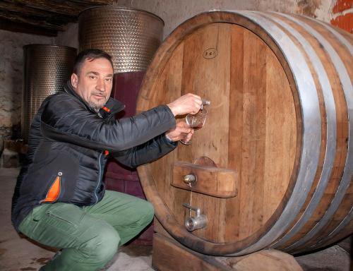 a man is holding a wine glass in front of a barrel at Rooms Agroturizam Romano in Buje