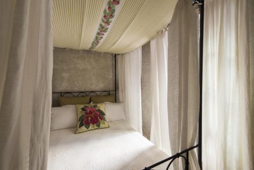 a canopy bed with white curtains and a flower pillow at Relais Del Maro in Borgomaro