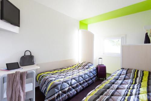 a bedroom with two beds and a desk with a tv at hotelF1 Besancon Ouest Micropolis in Besançon