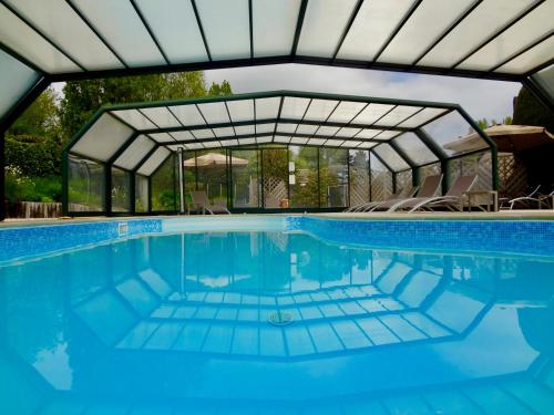 a swimming pool with a glass roof and chairs in it at Hotel Nuit Et Jour - La Maison de Lucile in Cancale
