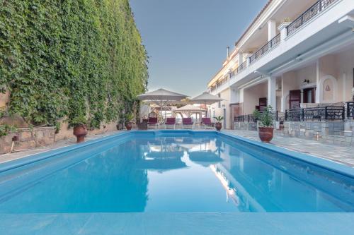 a swimming pool with blue water in front of a building at Aktaion Beach Boutique Hotel & Spa in Skala
