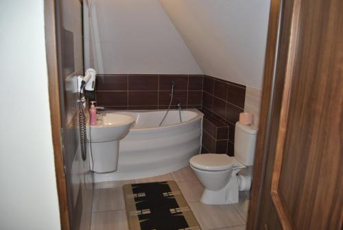 een badkamer met een bad, een toilet en een wastafel bij Zajazd Dworek in Mircze