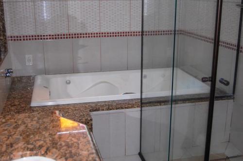 uma banheira na casa de banho com uma parede de vidro em Pousada do Sol em Penedo