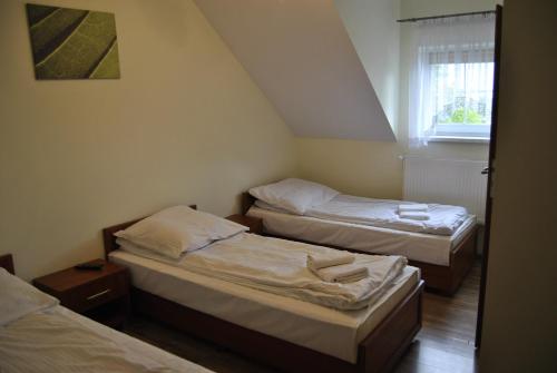 een kamer met 3 bedden en een raam bij Zajazd Dworek in Mircze