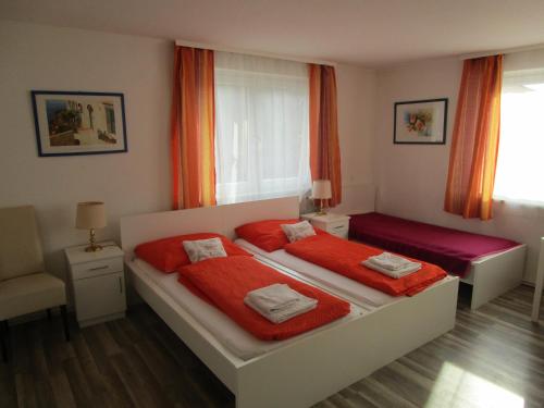 a bedroom with two beds and a window with orange curtains at Gasthaus Schwarzer Adler in Altenberg