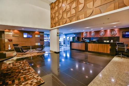 a lobby of a hotel with a reception desk and chairs at SJ Premium Hotels By Atlantica in Goiânia