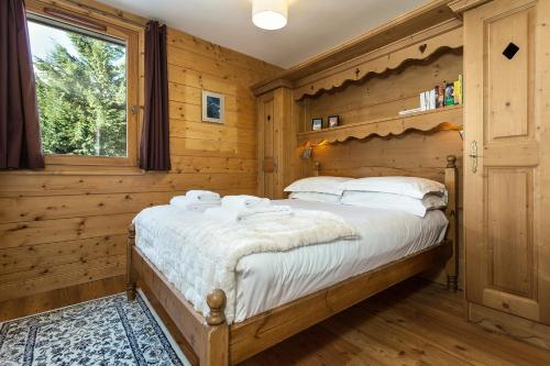 een slaapkamer met een bed in een houten kamer bij APARTMENT KANDAHAR - Alpes Travel - Central Chamonix - Sleeps 4 in Les Houches