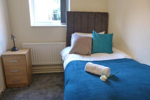 a bedroom with a bed with a blue comforter at Pageant Lodge in Telford