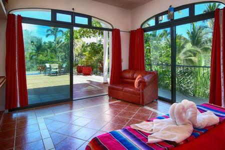 a living room with two beds and a couch and windows at Villas del Corazon - 8 Bedroom Villa in Sayulita