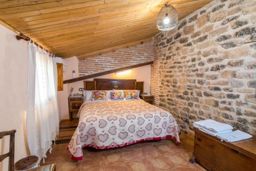 - une chambre avec un lit et un mur en briques dans l'établissement Casa rural Rosa, à La Fresneda