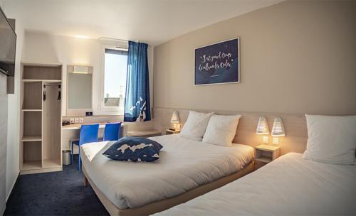 a hotel room with two beds and a desk at Ace Hôtel Paris Sud Villabe in Villabé