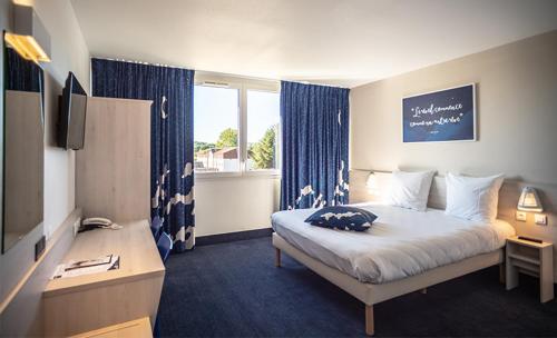 a bedroom with a bed and a desk and a window at Ace Hôtel Paris Sud Villabe in Villabé