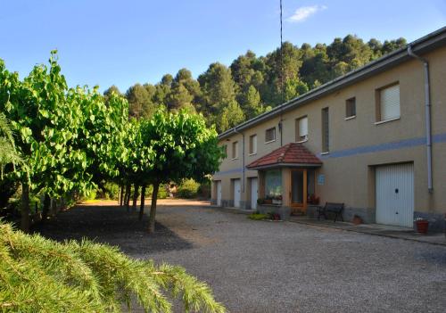 une rangée de bâtiments avec des arbres devant eux dans l'établissement Hostal El Violí, à Cardona