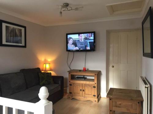 a living room with a couch and a flat screen tv at Awel Y Mor in Barmouth