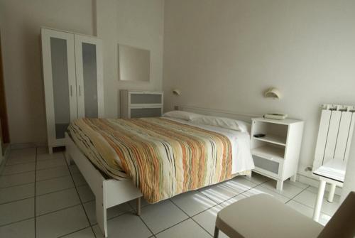 a white bedroom with a bed and a night stand at Hotel Annarita-mezza pensione plus- spiaggia inclusa in Rimini