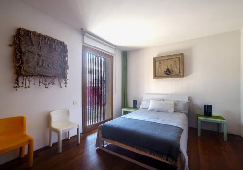 ein Schlafzimmer mit einem Bett, einem Stuhl und einem Fenster in der Unterkunft La Pigna in Cervia