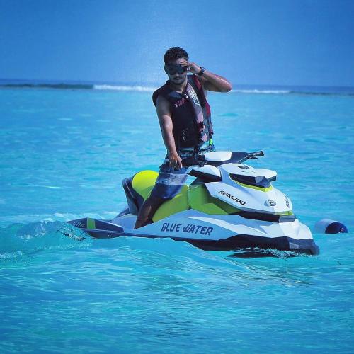 a man riding a jet ski in the water at Blue Water Thoddoo Inn in Thoddoo