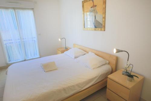 un lit avec des draps blancs et des oreillers dans une chambre dans l'établissement PALAIS LIBERTE, à Nice