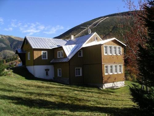 a house on a field with a hill in the background at Pension 48 in Špindlerův Mlýn