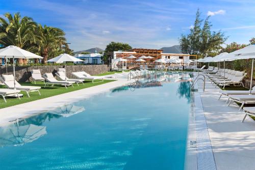 a large swimming pool with white chairs and umbrellas at Elba Premium Suites - Adults Only in Playa Blanca