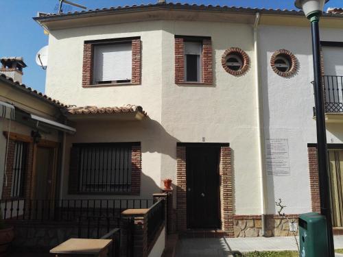 a white house with a black door and windows at Del Romero in Arroyo Frio