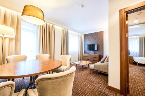 a hotel room with a table and chairs and a living room at Radisson Blu Hotel, Kyiv Podil City Centre in Kyiv