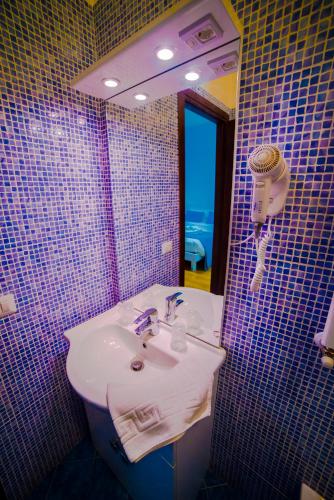 a bathroom with a sink and a purple tiled wall at Galleria Frascati Rooms and Apartment in Frascati