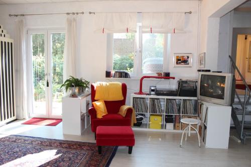 Bed & Breakfast Wesseloh في شنيفردينغين: غرفة معيشة مع كرسي احمر وتلفزيون