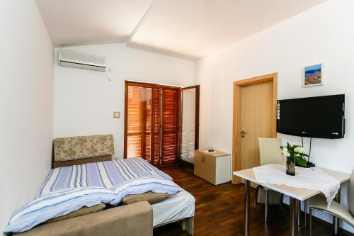 a bedroom with a bed and a table and a tv at Apartments Josip in Pinezici