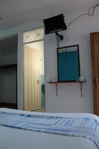 a room with a bed and a television and a mirror at Hotel Carruiz in Puerto Escondido