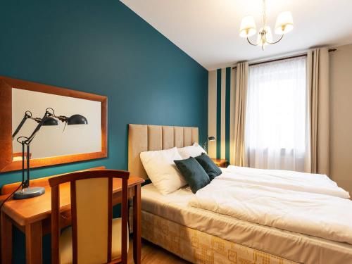 a bedroom with a bed and a desk with a lamp at VacationClub – Olymp Apartament 211 in Kołobrzeg