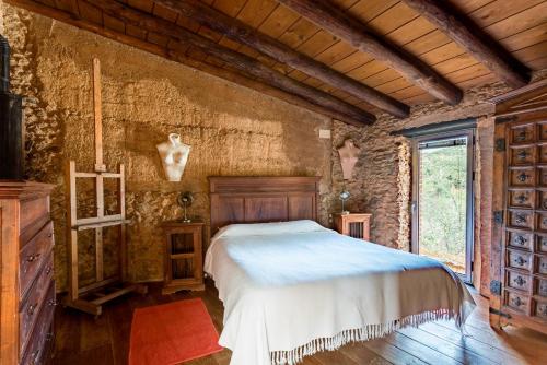 a bedroom with a bed in a stone wall at El Risco del Lomero in Valdelarco