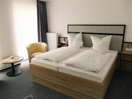 een slaapkamer met een groot bed met witte lakens en kussens bij Hotel Diekgerdes, Komfortzimmer in Cloppenburg