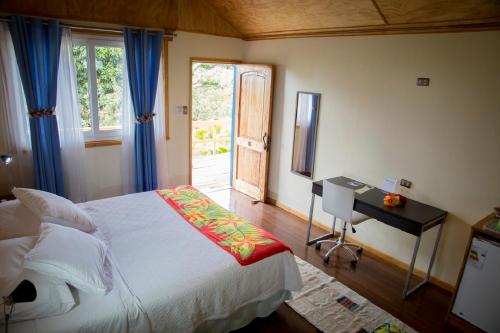 a bedroom with a bed and a desk and a window at Hotel Taura'a in Hanga Roa