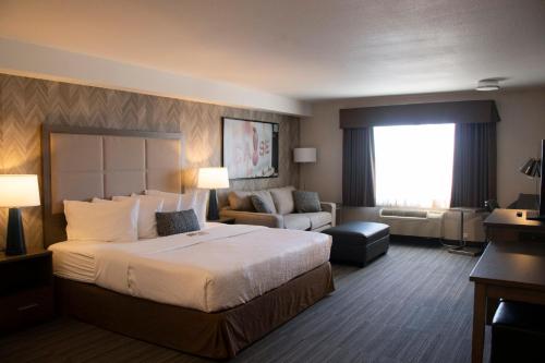 a hotel room with a large bed and a couch at Canalta Airdrie in Airdrie