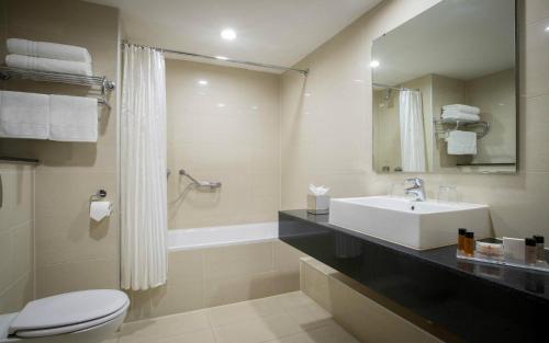 a bathroom with a sink and a toilet and a tub at Clayton Hotel Silver Springs in Cork