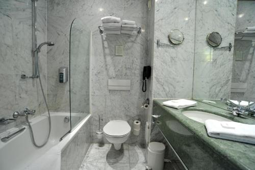 a bathroom with a toilet and a shower and a sink at Golden Tulip Hotel de’ Medici in Bruges