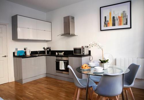 a kitchen with a glass table and chairs in a room at 1A, Opera House 1st Floor by Indigo Flats in London
