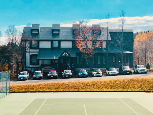 a house with cars parked in front of a tennis court at Appi Life is Beautiful in Hachimantai