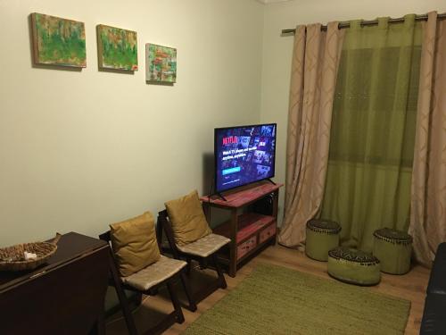 a living room with a flat screen tv and two chairs at Ria Apartments in Olhão