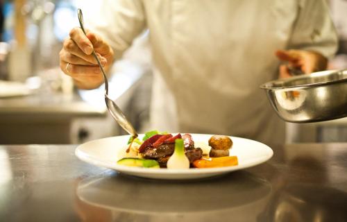 a chef preparing a plate of food on a counter at Sporthotel Neustift in Neustift im Stubaital