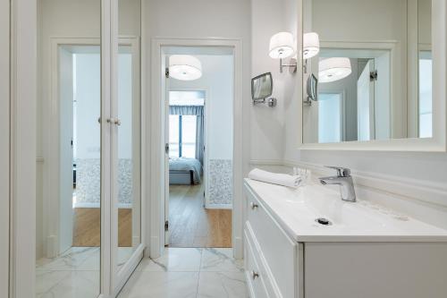 a white bathroom with a sink and a mirror at Airport Lirowa - P&O Serviced Apartments in Warsaw