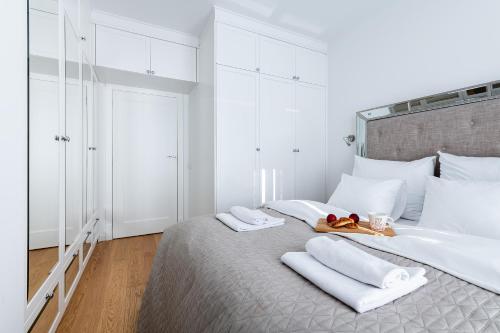 a white bedroom with a large bed with white pillows at Airport Lirowa - P&O Serviced Apartments in Warsaw