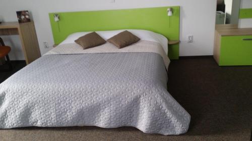 a bedroom with a white bed with a green headboard at Vila William’s in Braşov
