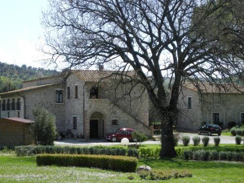 a large stone house with a car parked in the driveway at Villa Acquaviva Wine Resort in Montemerano