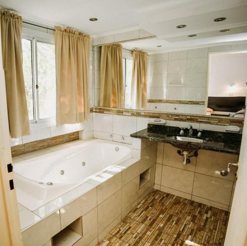 a white bathroom with a tub and a sink at La Candida Hotel in Merlo