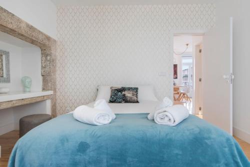 een slaapkamer met een blauw bed en handdoeken bij LovelyStay - Lusitano's Heart 2BDR Apartment in Alfama in Lissabon